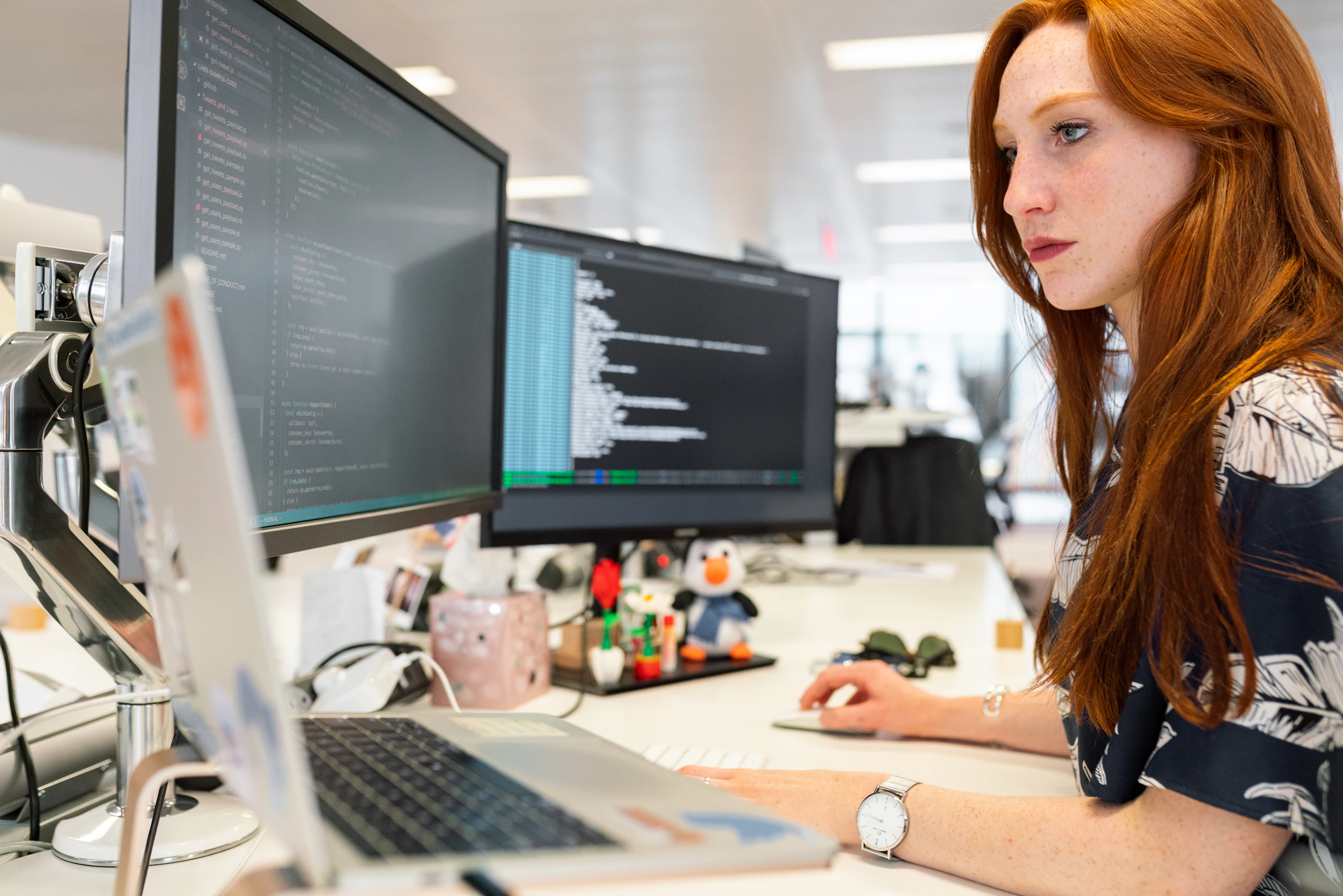 An engineer working at a desk with several monitors showing code