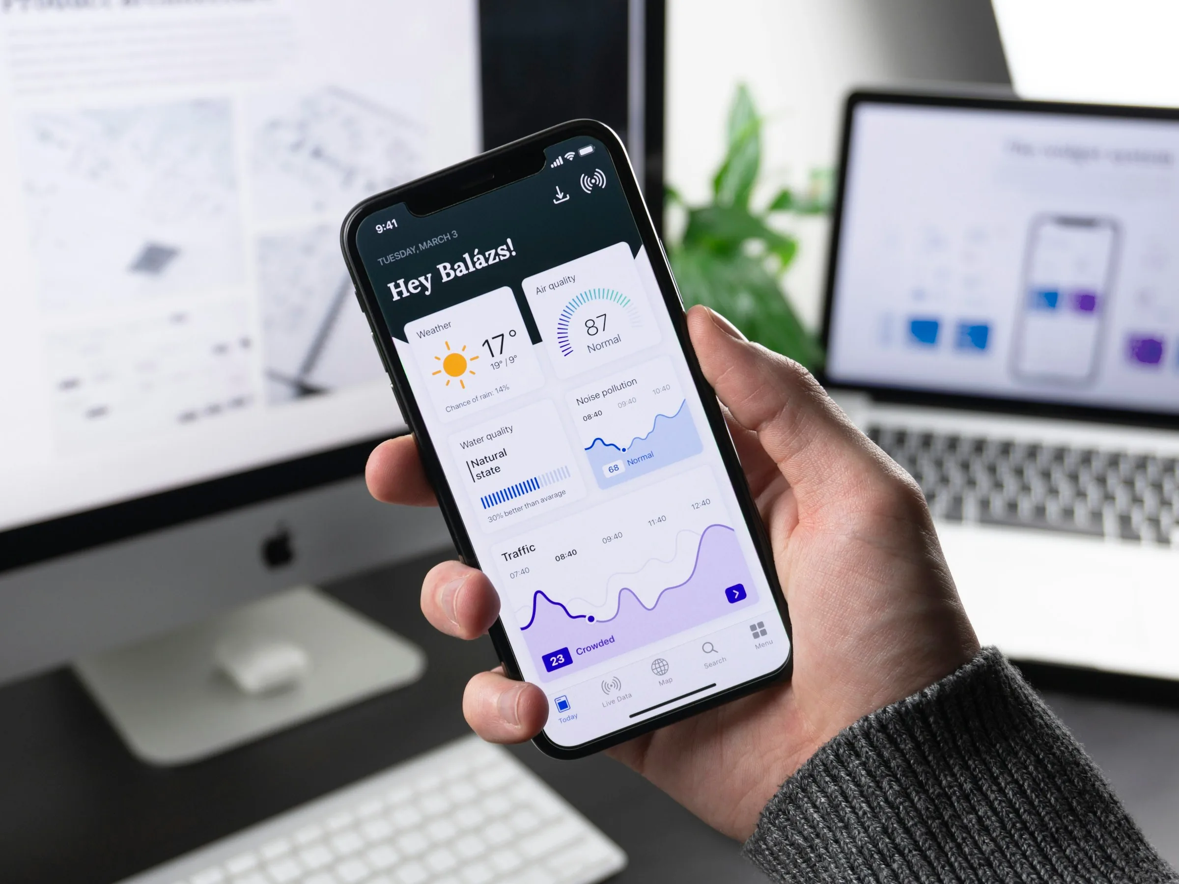 A hand holding a smartphone showing a data dashboard app