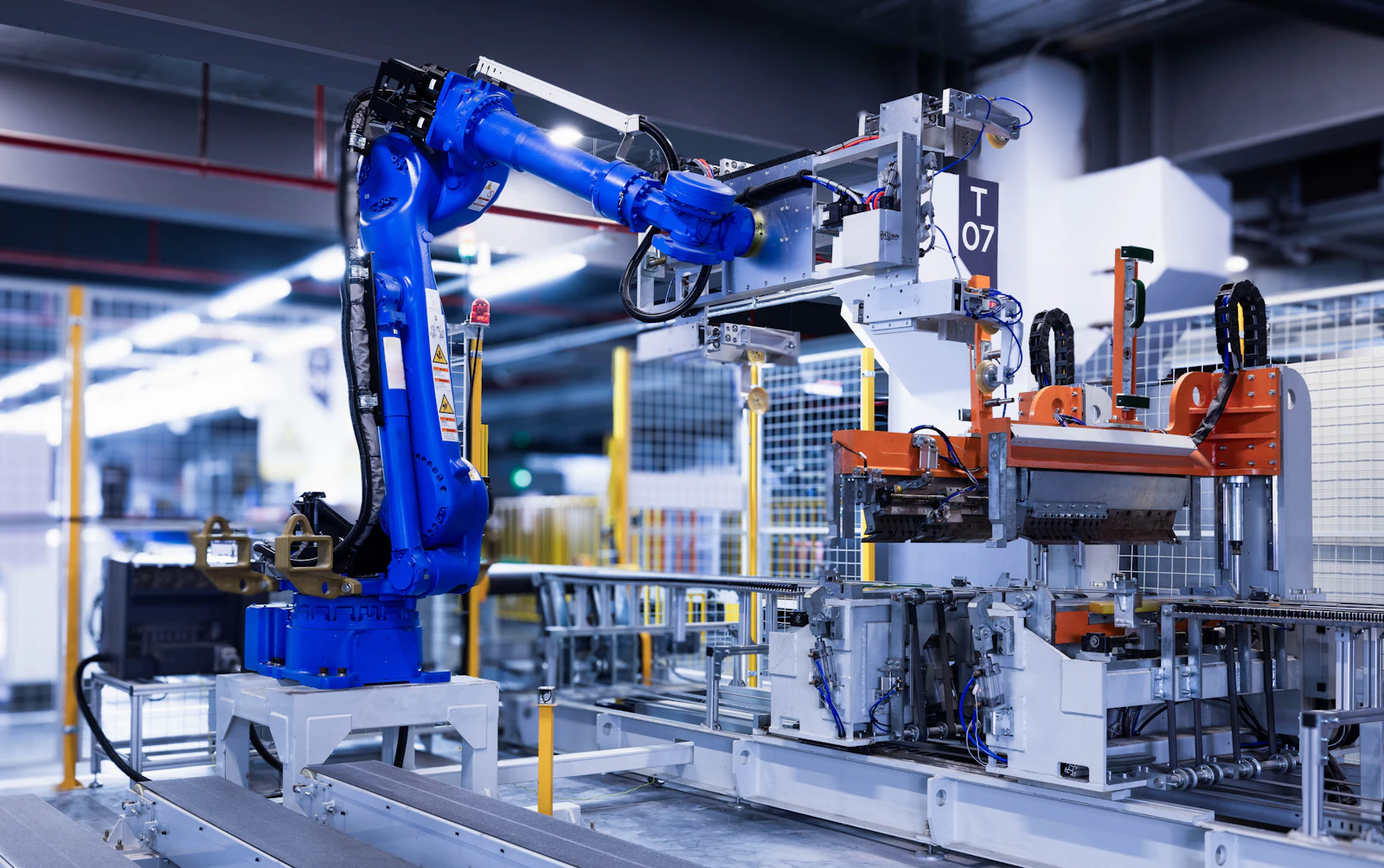 A blue industrial robot arm working on an automated production line