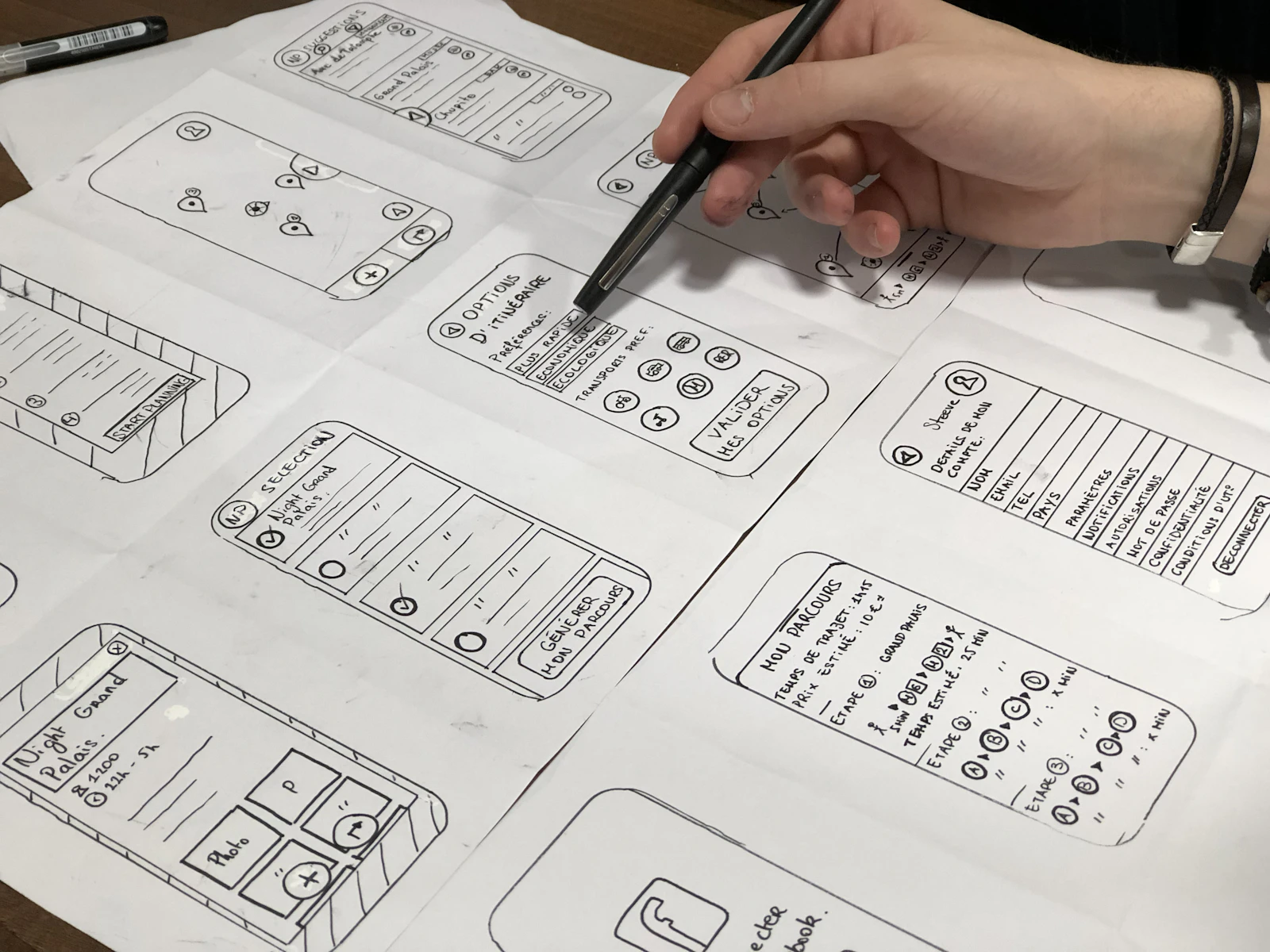 A hand sketching mobile app wireframes on paper